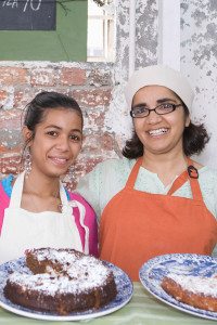 Two Female Restaurant Employees Smiling at the Camera Holding Desserts